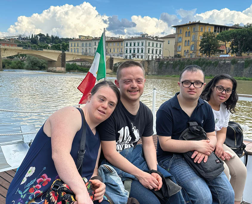 La foto mostra un gruppo di 4 persone con la sindrome di Down, due uomini e due donne, durante una gita in battello.