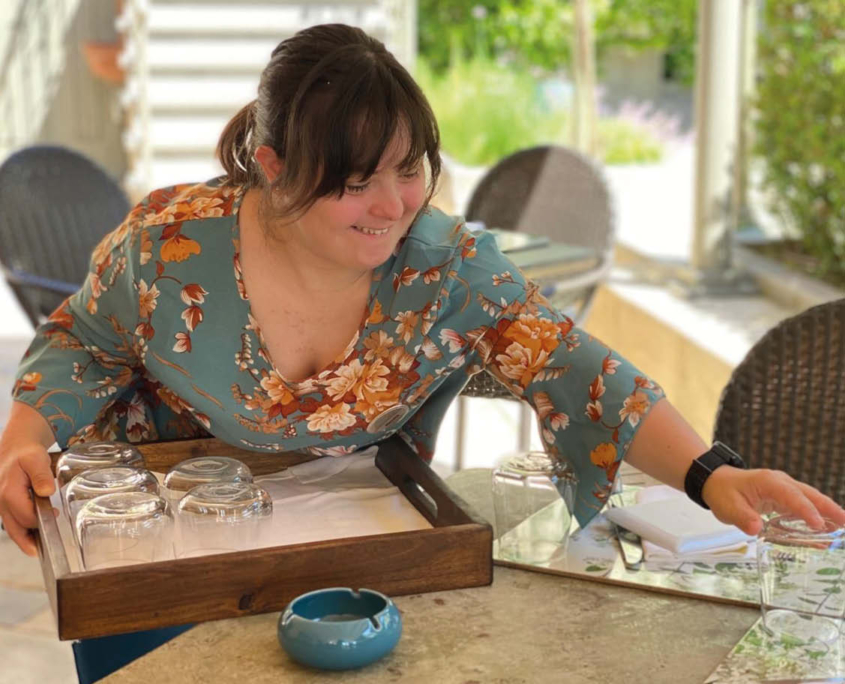 Una giovane donna apparecchia la tavola durante il suo orario di lavoro.