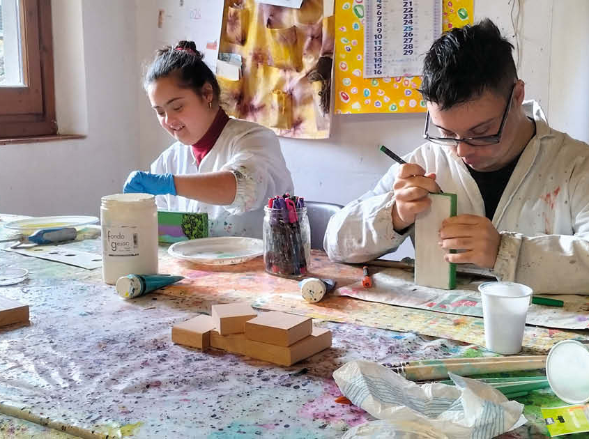 Una giovane donna e un ragazzo completano un lavoro durante l'attività di laboratorio di Trisomia 21 aps.