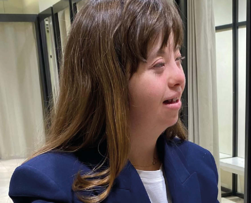 Una giovane donna, che indossa una giacca blu, sorride all'inizio del suo percorso di affiancamento lavorativo.