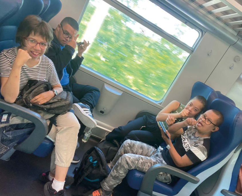 Quadro ragazzi, due ragazze e due ragazzi, in treno, in treno durante un'uscita nell'attività di autonomia e pre-autonomia.