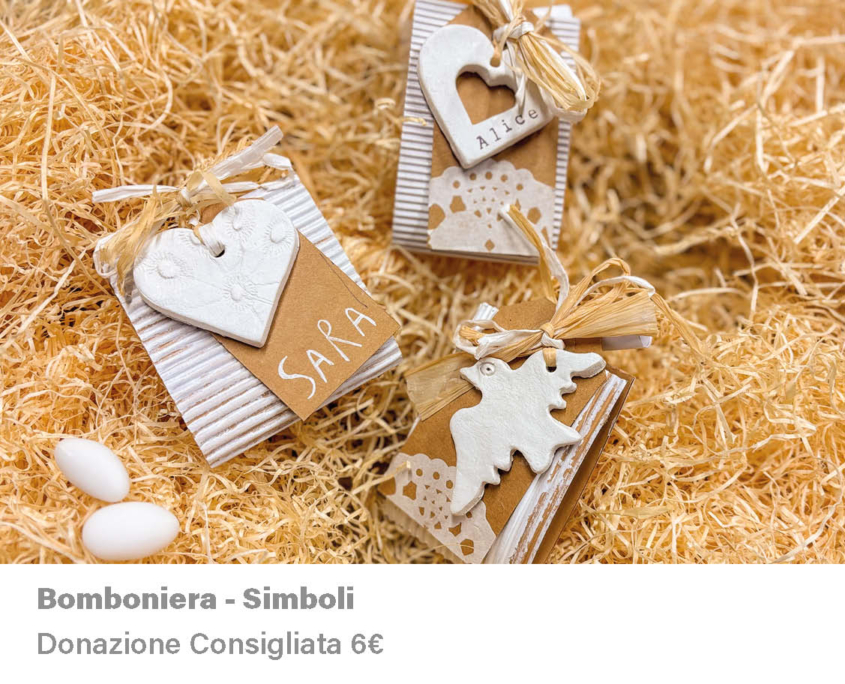 Composizione fotografica di tre bomboniere di cartone. Ogni bomboniere ha legato una forma di pasta modellante (DAS). Le forme sono tre: due cuori, uno di questi forato e un uccello. Le forme sono bianche. Le bomboniere sono disposte su una superficie di paglia, insieme a due confetti bianchi.