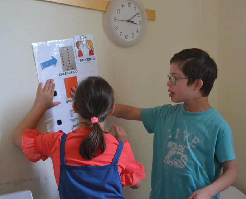 Una bambina e un bambino, completano un esercizio durante l'attività di Potenziamento Cognitivo.